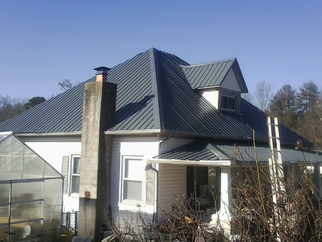 Dark blue standing seam metal roof on a white farmhouse with dormer — Slate & Tile Roof Repair by Roofing Brothers in Stoystown