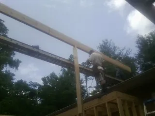 Carpenter setting a ridge beam over a new addition frame — Ice Dam Removal by Roofing Brothers in Stoystown