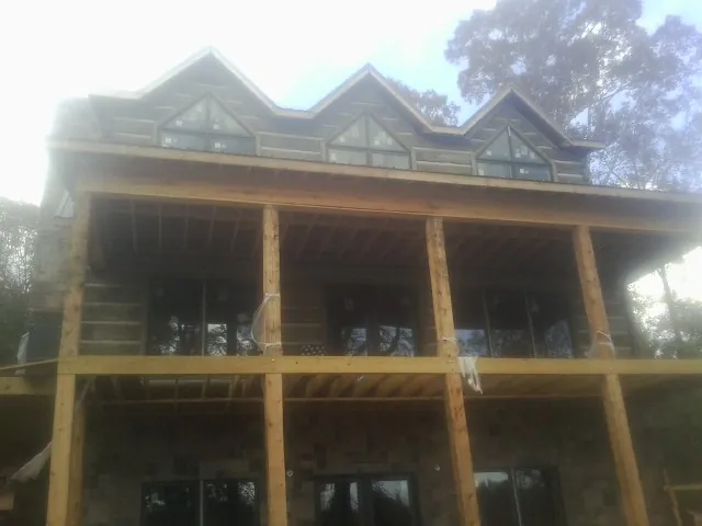 Dormers and porch framing on a large log home under construction — Roof Coating work by our crew in Stoystown