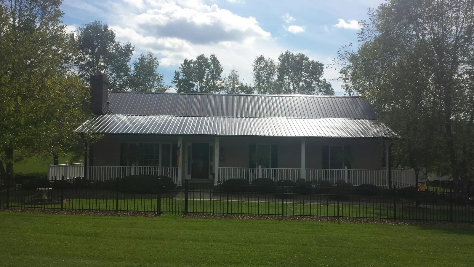 Gray metal roof on a brick ranch with a full width front porch — Gutter Guard Installation work by our crew in Stoystown