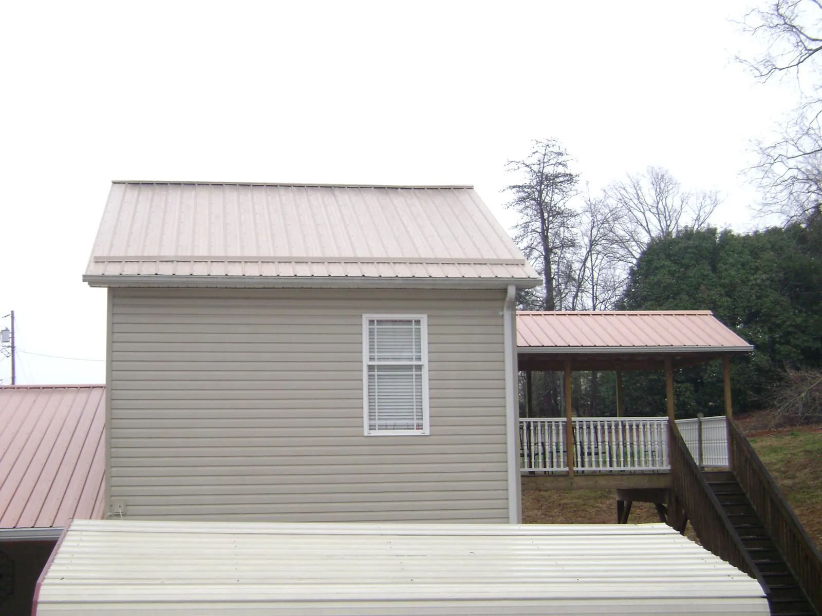 Tan metal roofs on a two story addition and attached porch, from a Roof Replacement job in Stoystown